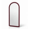 An arched wall mirror with a dark burgundy beaded frame, shown on a clean white background with a soft reflection underneath.